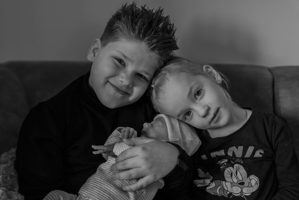 Broertje en zusje houden newborn vast